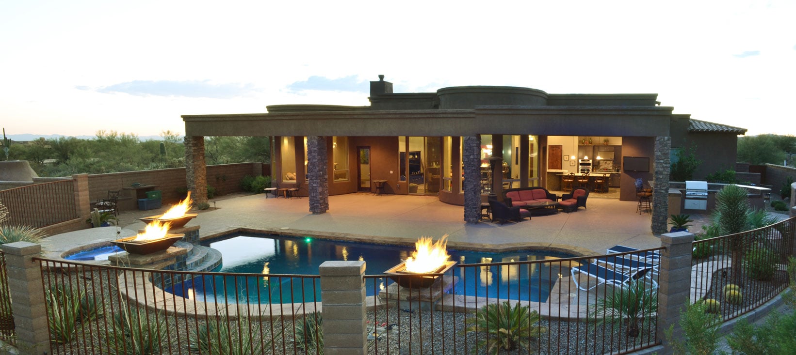 Commanding full length patio off dual radius windowed rooms overlooking custom pool with fire po